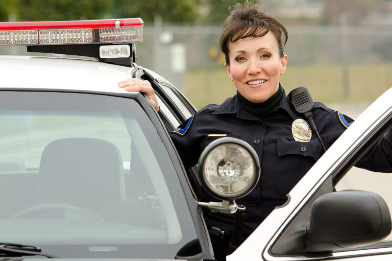 Smiling, female officer with her patrol car